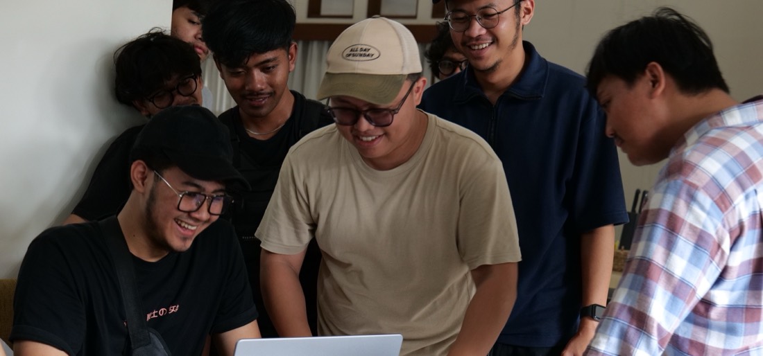 A team gathered around a laptop, working through something together