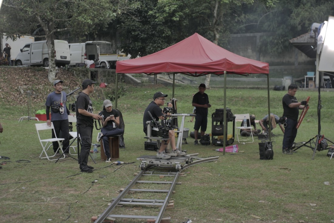 A film crew setting up camera track and lights on location