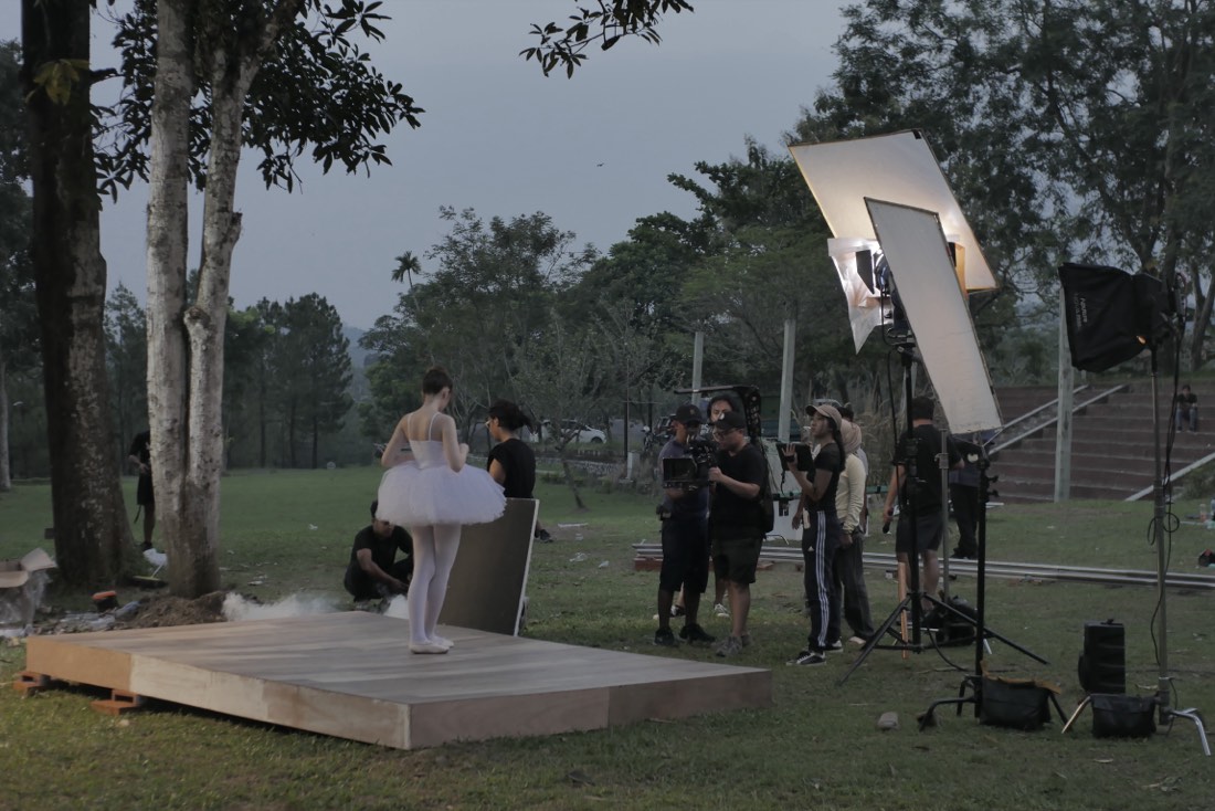 A crew filming a performer on an outdoor set at dusk