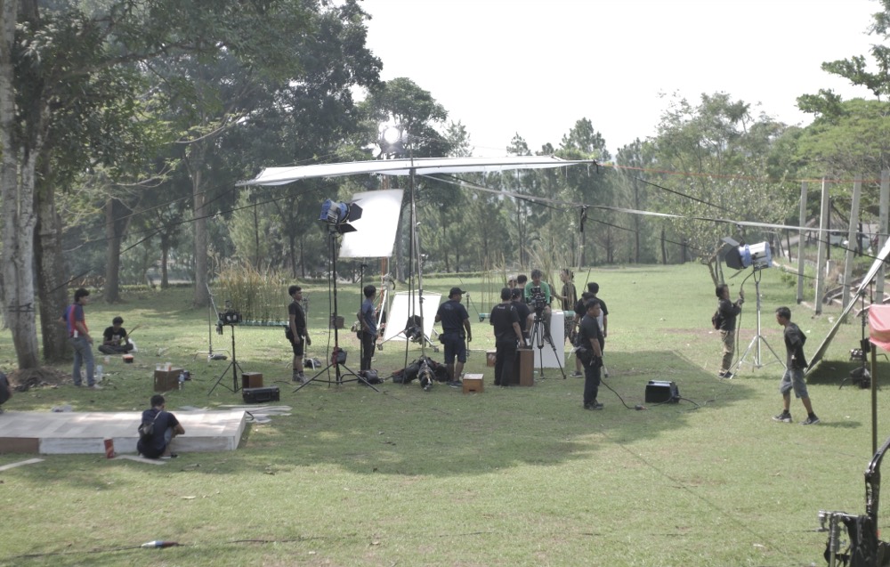A film crew setting up lights and camera on an outdoor location